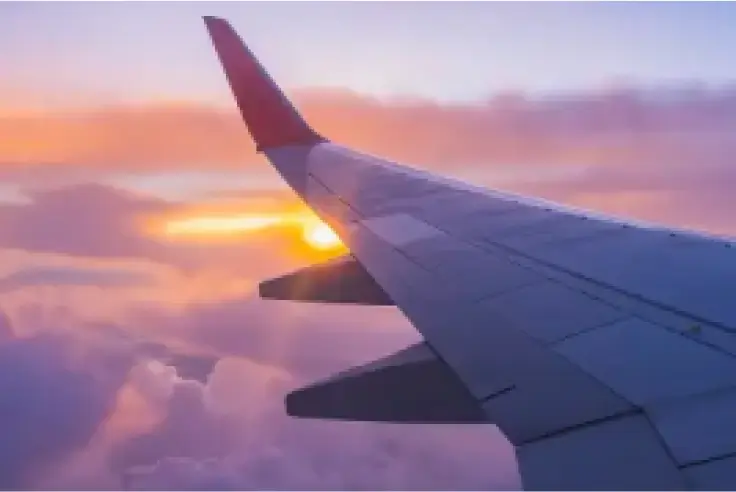 View of an airplane wing during sunset over the clouds.
