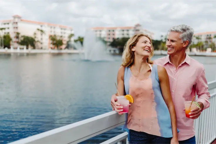 happy couple enjoying colorful drinks by the waterfront