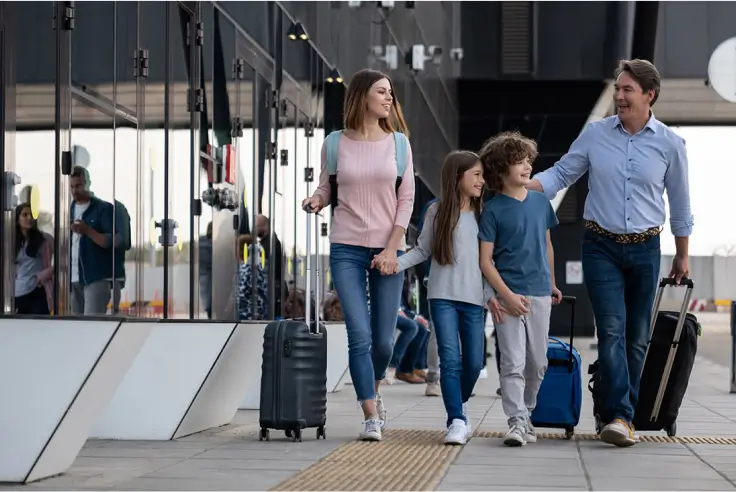 Happy family walking through the airport with luggage.