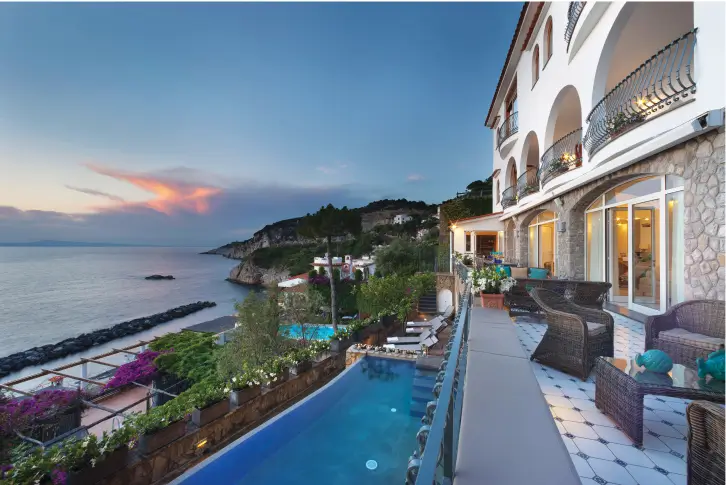 A stunning luxury villa with an ocean view and pool at sunset.